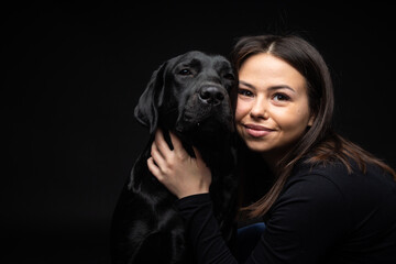 A girl holds a Labrador Retriever dog in her arms.