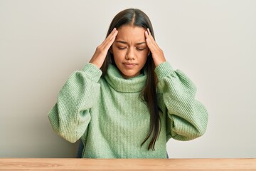 Sticker - Beautiful hispanic woman wearing casual clothes sitting on the table with hand on head, headache because stress. suffering migraine.