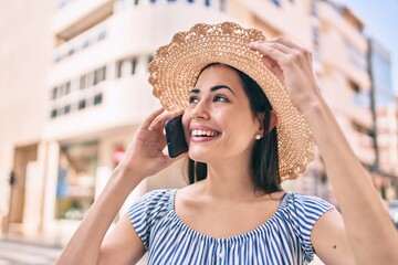 Wall Mural - Young latin tourist girl on vacation smiling happy  talking on the smartphone at the city.