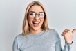 © Krakenimages.com - Young caucasian woman wearing casual clothes and glasses pointing thumb up to the side smiling happy with open mouth