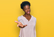© Krakenimages.com - Young african american girl wearing casual clothes smiling cheerful offering palm hand giving assistance and acceptance.