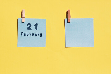 21st of February. 21st day of the month, calendar date. Two blue sheets for writing on a yellow background. Top view, copy space. Winter month, day of the year concept