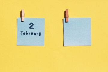 2st of February. 2st day of the month, calendar date. Two blue sheets for writing on a yellow background. Top view, copy space. Winter month, day of the year concept