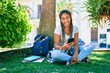 © Krakenimages.com - Young african american student woman smiling happy using smartphone sitting on the grass at the university campus