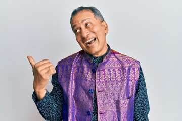 Poster - Middle age indian man wearing traditional indian clothes pointing thumb up to the side smiling happy with open mouth