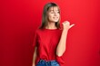 © Krakenimages.com - Teenager caucasian girl wearing casual red t shirt pointing thumb up to the side smiling happy with open mouth