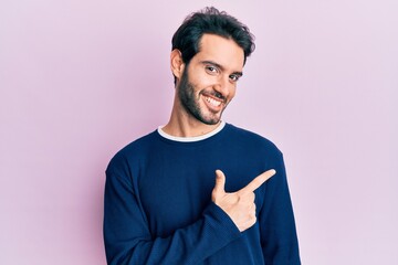 Sticker - Young hispanic man wearing casual clothes smiling cheerful pointing with hand and finger up to the side