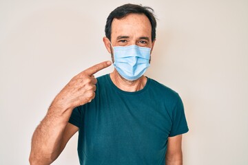 Poster - Middle age hispanic man wearing medical mask smiling happy pointing with hand and finger