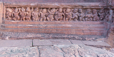 Wall Mural - Badami, Karnataka, India - November 7, 2013: Cave temples above Agasthya Lake. Closeup of restone sculpture of row of small human figures dancing and being merry.