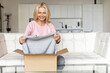 © Vadim Pastuh - Happy with delivery satisfied female customer unpacking cardboard box, excited middle-aged woman glad to get a parcel, order online, sitting on the couch at home