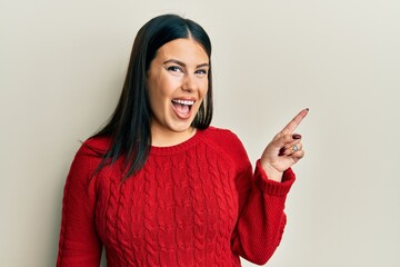 Sticker - Beautiful brunette woman wearing wool winter sweater with a big smile on face, pointing with hand and finger to the side looking at the camera.