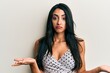 © Krakenimages.com - Beautiful hispanic woman wearing casual clothes clueless and confused expression with arms and hands raised. doubt concept.