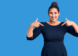 Young beautiful brunette woman wearing casual dress looking confident with smile on face, pointing oneself with fingers proud and happy.