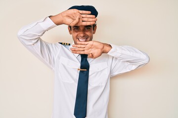 Sticker - Young hispanic man wearing airplane pilot uniform smiling cheerful playing peek a boo with hands showing face. surprised and exited