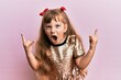© Krakenimages.com - Little caucasian girl kid wearing festive sequins dress shouting with crazy expression doing rock symbol with hands up. music star. heavy concept.