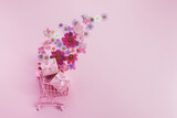 Fototapeta Mapy - Flowers fly out of the pink shopping cart on a pink background. Season sale, spring shoping concept. Valentines day.