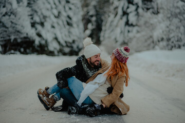 Canvas Print - Beautiful couple sitting on the ground outside wearing warm clothes for winter and having fun