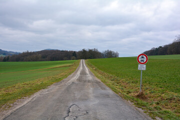 Narrow empty country road in Germany with a street sign