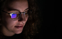Computer Screen Reflected In The Glasses Of A Woman Who Works At Night. Overwork