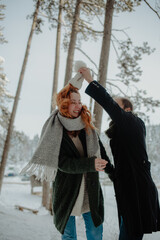 Beautiful view of a couple wearing warm clothes, dancing and having fun at the snow park