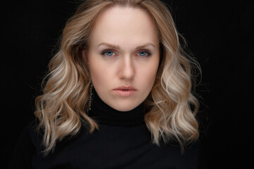 Perfect portrait of a white woman on a black background. Beautiful blue eyes, natural beauty of clean skin, face and hair care. Strong, thick hair.