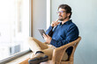 © Joao - Casual business man wearing glasses sitting holding his tablet. Successful male portrait with thinking face expression working from home by the window