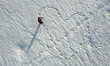 Luftaufnahme mit einer Drohne von einer Schneeschuhläuferin die eine Spur in Form von einem Herz in den Schnee gelaufen hat