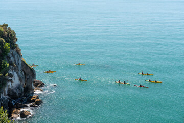 An elevated view of a group of kayakers rounding Pitt Head, Able Tasman National Park, New Zealand. 