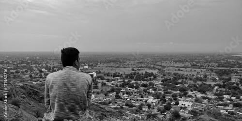 Rear View Of Man Looking At Cityscape Against Sky