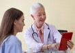 © Bangkok Click Studio - Senior older female doctor taking, explaining and history taking with a patient with a smiley face and intimate manner
