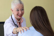 © Bangkok Click Studio - Senior older female doctor taking, explaining and history taking with a patient with a smiley face and intimate manner. She touches the shoulder's patient with a kind gesture.