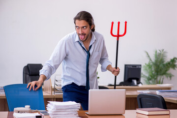 Young devil businessman holding trident in the office