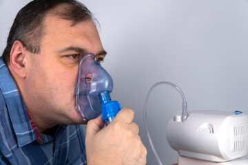 man holds a breathing mask and inhales. nebulizer and Oxygen Mask. spraying of a drug that is delivered to the patient through a mask or breathing tube