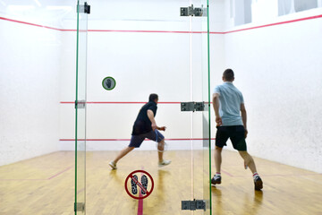 Squash player in action reaching on squash court. Out of focus