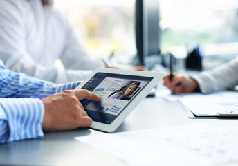 Close up of person video conferencing with colleagues on digital tablet, analyzing financial statistics displayed on the digital tablet screen.