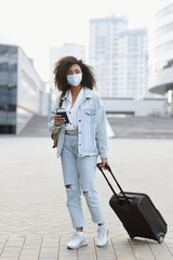 Wall Mural - Young woman tourist holding passport and ticket, girl wearing protective face mask in a city, Business travel during pandemic, corona virus protection, healthy lifestyle, people, tourism concept