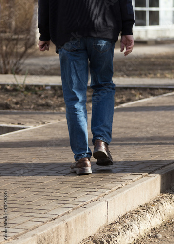 Man's legs in blue denim jeans and brown boots. © indigolotos
