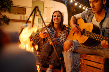 Wall Mural - friends playing on guitar by the bonfire, camping