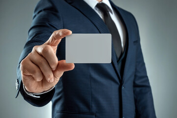 A man in a suit hands close-up shows a business card. mockup, layout. Concept for networking, business dating, important connections. Shot on a gray background.