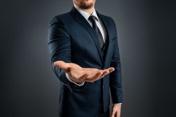 Male hand in a suit shows a palm up gesture on a gray background. Concept of request, bankruptcy, close-up.