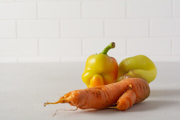 Two ugly peppers and carrots that looks like a strange face on a light table. Funny, unnormal vegetable or food waste concept.