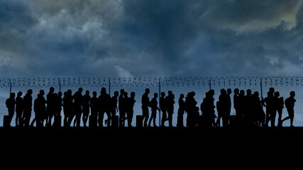 Refugees and immigrants looking for a new life. Column of migrants near the state borders. Fence and barbed wire. Surveillance, supervised. Abandon their lands for a better future. Silhouette