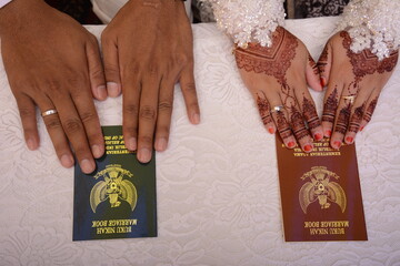 Malang, Indonesia - 28 January 2021: close-up of the Indonesian government's official marriage book and henna decorated hands.