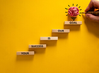 Wall Mural - Business concept growth success process. Wood blocks stacking as step stair on yellow background, copy space. Businessman hand. Words 'your success is our goal'. Conceptual image of motivation.