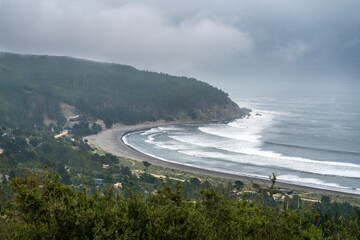 A dramatic view of Puertecillo surf spot. An idyllic place for practising surfing on an amazing natural place surrounded by the forest and the Pacific Ocean. A cloudy day view during morning time