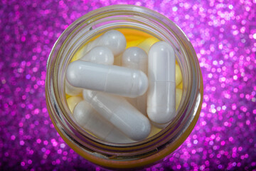 White Pills In Yellow Glass Jar on Purple Background