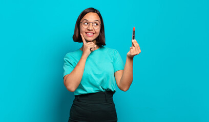 young hispanic woman smiling happily and daydreaming or doubting, looking to the side