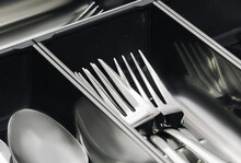 Stainless steel Kitchen utensil cutlery drawer organizer tray with simple set of tools, spoons and forks. Close up