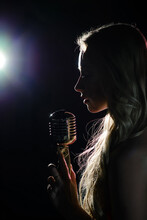 Silhouette Of The Singer With A Microphone On Dark Background