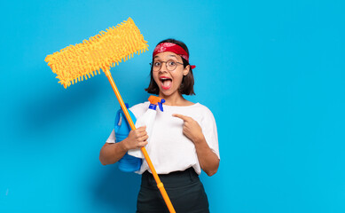 Canvas Print - young latin woman looking excited and surprised pointing to the side and upwards to copy space